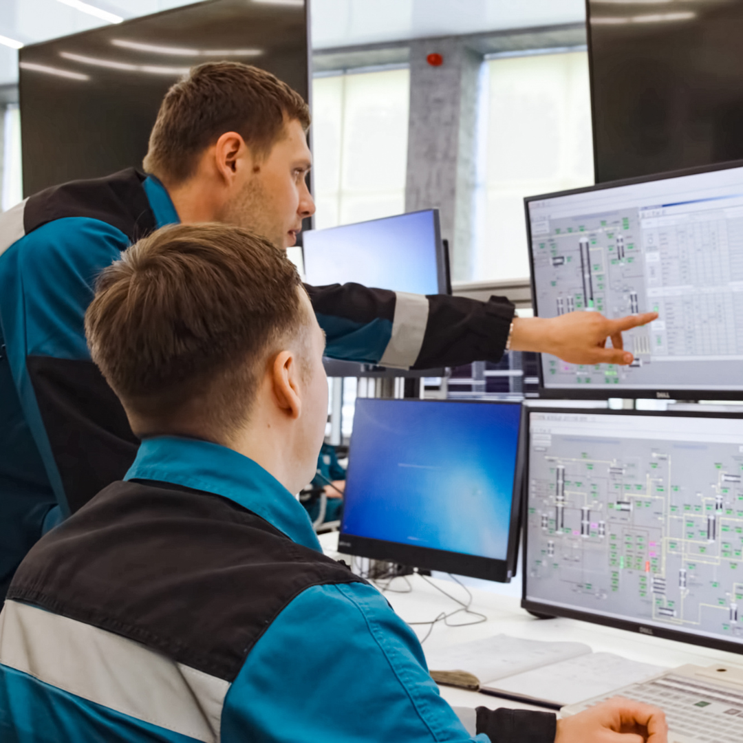 Two engineers looking intently on a computer with schematics on the screen.